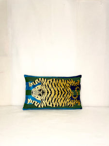 Schumacher Tiger pillow is gold with black stripes on the tiger and green and blue stripes behind the tiger. 